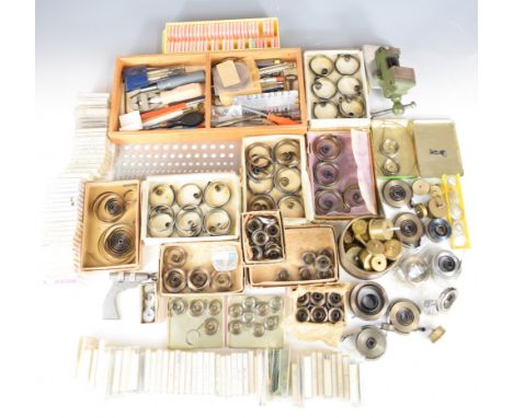 Collection of watch parts and tools including mainsprings, precision measuring devices, vices etc
