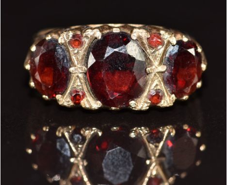 A 9ct gold ring set with three large oval cut garnets and four round cut garnets, 4.5g,&nbsp;size O/P