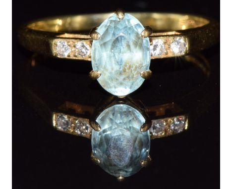 An 18ct gold ring set with an oval cut aquamarine and diamonds, 2.3g, size J