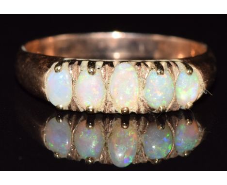A 9ct rose gold ring set with five opals, 1.7g, size N