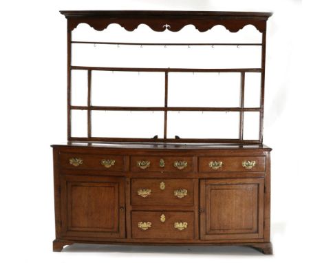 A George III Enclosed Dresser, circa 1800, the rack with moulded cornice and arched frieze above a shelf with cup hooks, the 