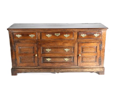 A George III Oak Enclosed Dresser Base, mid 18th century, with plank top and moulded edge above three frieze drawers and two 