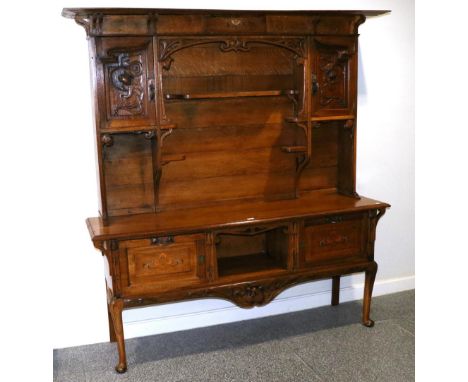 A Scottish Art Nouveau Carved, Metal and Marquetry Inlaid Oak Sideboard, the upper section with overhanging top, above an ope