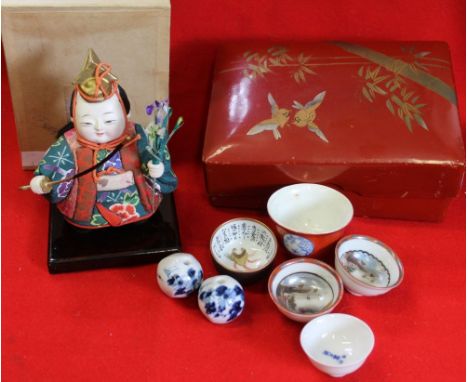 A Japanese mid-20th century doll in original box, a collection of five porcelain tea / Saki cups in lacquer box. together wit