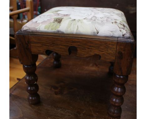 A small carved oak footstool with bobbin turned legs and upholstered top