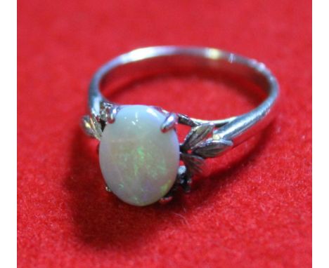 An opal set white metal ring, (stamped 18k, but tested as silver) Ring size M ½ Opal good, a little loose in setting. Scratch