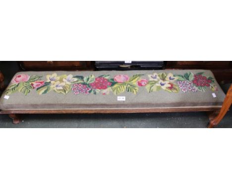 An oak framed long low foot stool with tapestry top