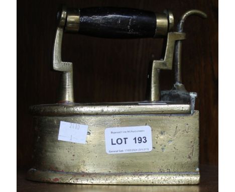 A brass flat iron, having opening section for heated item and wooden handle