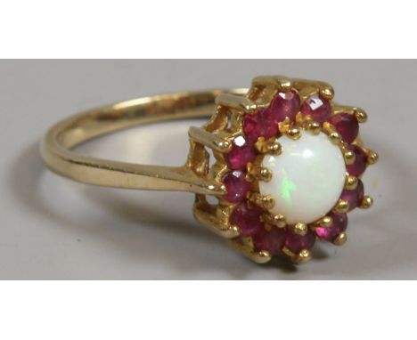 A ladies 9ct gold ring set with an opal with a halo of rubies, size O.