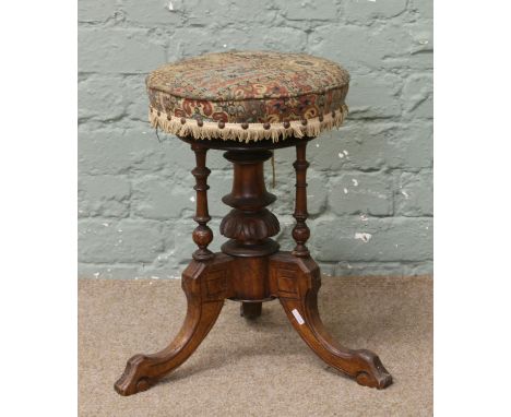 A Victorian carved walnut adjustable piano stool.