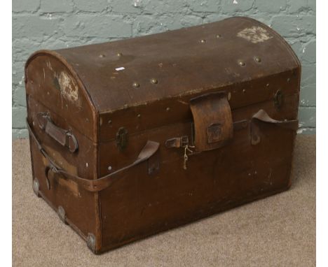 A canvas leather bound dome top travel trunk with heavy leather straps and lock protector and removable tray.