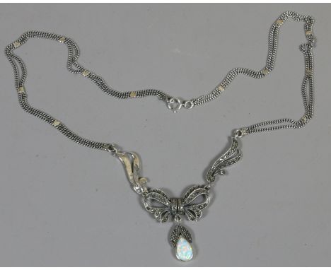 A silver necklace with opal pendant on marcasite bow setting.