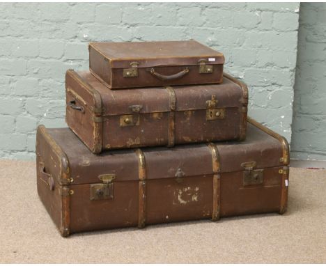 A wooden bound travel trunk, a smaller trunk and a small leather suitcase.