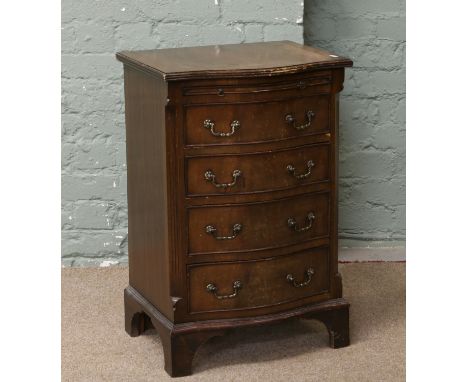 A mahogany serpentine batchelors chest of four drawers incorporating a brushing slide, crossbanded with canted corners and ra