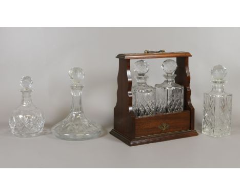 A mahogany two bottle tantalus, a ships decanter and two other cut glass decanters.