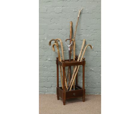 A mahogany stickstand raised on turned legs with tin liner and a quantity of sticks including shooting stick.