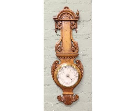 A C19th oak banjo barometer with heavily stylized decoration (AF).