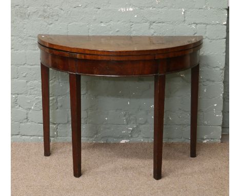 A Georgian mahogany bow front fold over card table raised on square tapering supports.