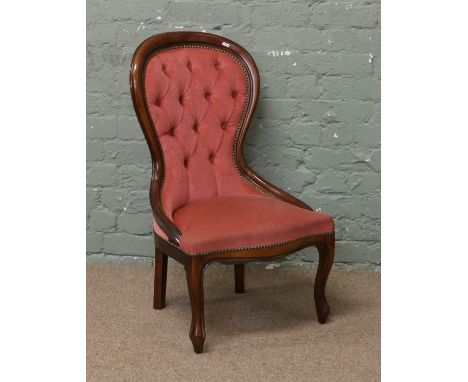 A spoon back nursing chair with deep buttoned upholstery.