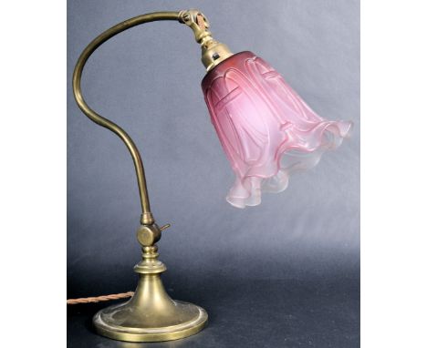An early 20th Century vintage brass desk lamp having a pressed two tone pink and frosted glass shade mounted on a shade brass