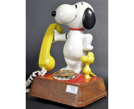 A retro vintage 1970's novelty Snoopy telephone raised upon a wooden base with a number dial to the front and Snoopy and Wood