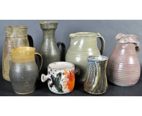 A mixed collection of 20th Century studio art pieces, mostly jugs to include a green glazed Leach Pottery example with impres