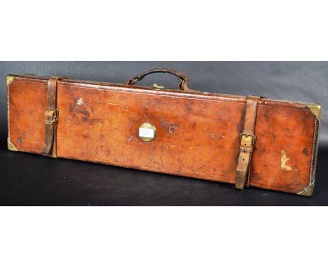 A vintage early 20th Century leather attache type shotgun / gun case. The case of rectangular form with unengraved circular b