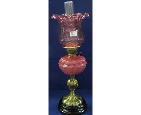 Early 20th Century brass double burner oil lamp, having pink fluted glass reservoir on a fluted brass baluster stem with blac