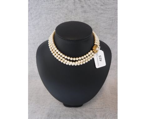 A TRIPLE STRAND CULTURED PEARL CHOKER, terminating on to an unmarked yellow metal clasp set with a single pearl