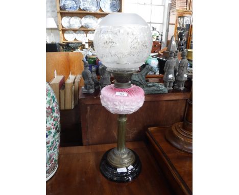A VICTORIAN OIL LAMP, with a brass column, pink glass reservoir and frosted shade (not drilled but with an electric burner)