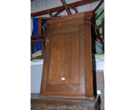 A Georgian Oak Wall hanging Corner Cupboard with moulded cornice over single moulded panel door opening to reveal painted int