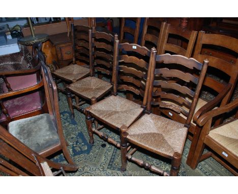 A set of four reproduction Clisset style Dining Chairs having ladder backs with five shaped bars, rush seats, standing on tur