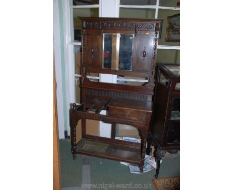 A 1940's Oak Hall Stand with mirrored back, applied carving to the flanking panels, with lower stick stand to one side and ke