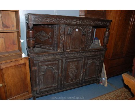 A 19th c. Oak Court Cupboard with carved crown on baluster turned supports, upper single panel door flanked by angled panels 