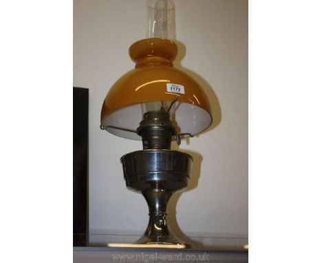 A chrome oil mantle lamp with mustard coloured shade.