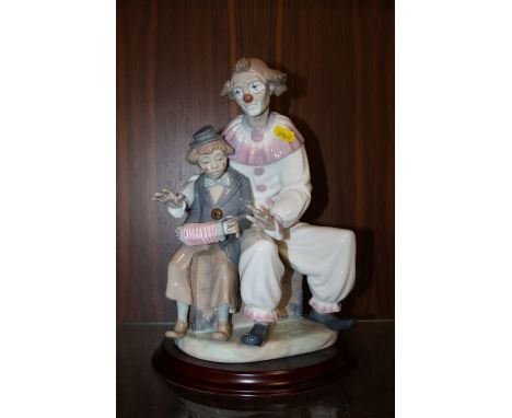 A LARGE NAO CLOWN WITH YOUNGER CLOWN RAISED ON A WOODEN PLINTH