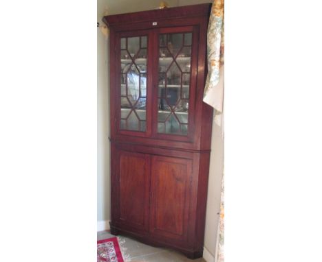 A 20th Century Mahogany Two Section Standing Corner Cabinet, the upper section fitted with three shelves enclosed by a pair o