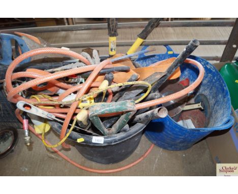 A bucket containing various tools to include loppers, saws, spades, welding rods, hosepipes etc.