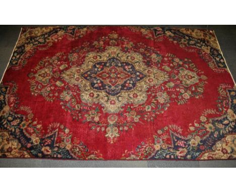 A red ground antique Tabriz hand woven carpet with some wear.