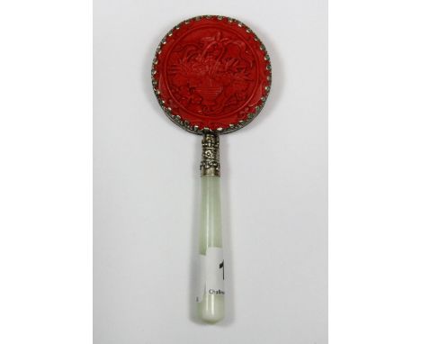 A small Chinese hand mirror backed with cinnabar style decoration and a jade handle, L. 14cm.