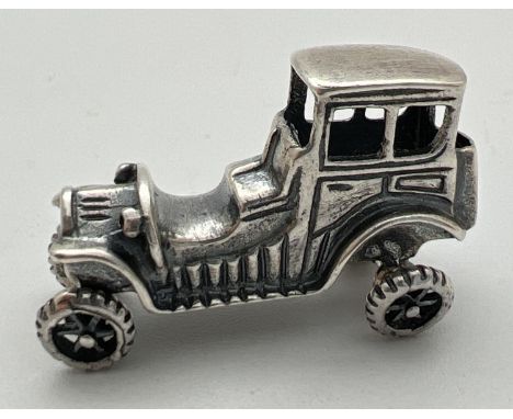 A small 925 silver model of a vintage veteran car with moving wheels. Stamped 925 to underside. Approx. 2cm tall x 3.25cm lon
