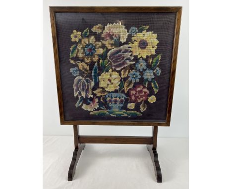 An Art Deco dark wood framed tilt top firescreen table with floral design needlepoint panel behind glass. Labelled to reverse