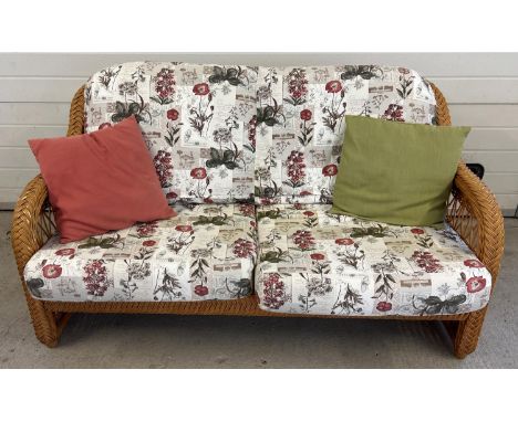 A modern light wood wicker 5 piece conservatory set with floral upholstered cushions. Comprising sofa, 2 x armchairs, large o