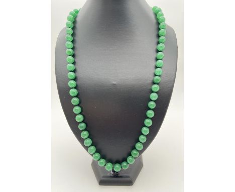 A 26" string of apple green jade beads, knotted between each bead. Beads approx. 1cm diameter. 