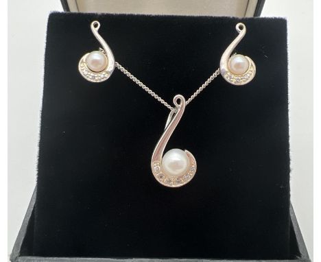 A modern design swirl design pendant necklace and matching earrings. Each set with a single pearl and small white stones. Pen