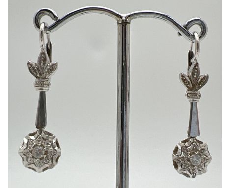 A pair of vintage 18ct white gold drop earrings set with a single round cut clear topaz stone to each. Floral detail to top o