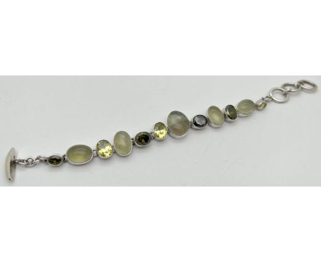 A modern design stone set bracelet with T Bar style clasp. Bracelet set with 7 bezel set faceted light and dark green topaz s
