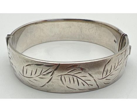 A vintage silver bangle with half engraved leaf decoration and slide push clasp. Hallmarked to inside for Birmingham 1972, 1.