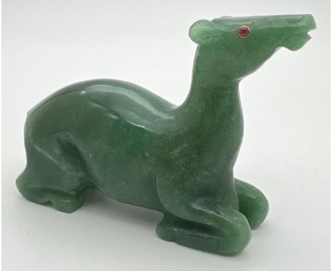 A carved jade figure of a deer, with ruby set eye (one missing). Approx. 6cm tall x 8cm long. 