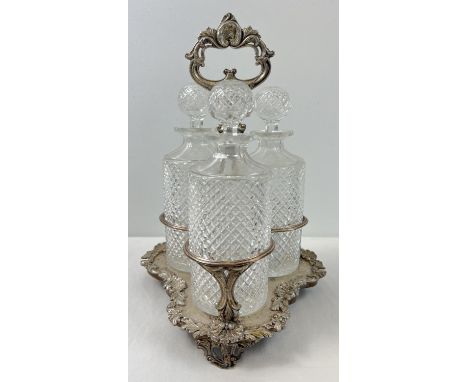 A vintage silver plated triple decanter stand complete with 3 cut glass decanters with cut diamond pattern. Floral and scallo